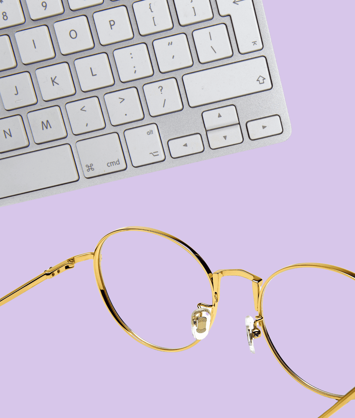 Goldene Brille und Tastatur auf lila Hintergrund